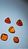 Five natural Ethiopian fire opal cabochon gemstones arranged on a plain background to show shape, color, and transparency.