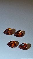 Four natural imperial sapphires pear cut laid flat, showing color and cut details under light.