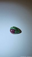 Top-down view of pear-shaped ruby zoisite gemstone with distinct red ruby section and green zoisite matrix.