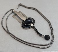 Close-up pendant and part of chain laid flat showing texture of chain and pendant design.