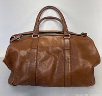 Front view of brown leather Fossil duffel bag with double handles and zip closure