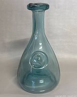 Front view of the blue Viking glass decanter showing the embossed Viking ship medallion centered on the round body.