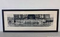 Framed panoramic black and white photo of a football team posed outside a building, centered and fully visible.