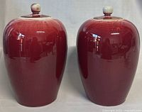 Front view of two red Sang De Boeuf glazed ginger jars with lids in place, showing glossy finish.