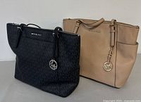 Black and beige Michael Kors tote bags together showing front and side profiles