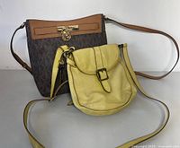 Both Michael Kors and Fossil crossbody bags together on display, showing size difference and overall condition.