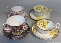 Photo showing all four Royal Albert teacup and saucer sets displayed. Four cups with distinct floral designs and matching saucers.