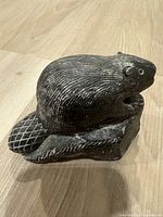 Side view of the hand-carved soapstone beaver figurine showing detailed tail texture and the beaver gnawing wood posture.