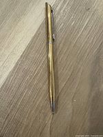 Full length view of the gold plated Montparnasse S.T. Dupont ballpoint pen showing body, tip, and clip on wood surface.