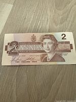 Front of the 1986 Canadian 2 dollar bill showing Queen Elizabeth II portrait and denomination 2.