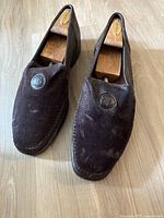 Front angled view of the pair of brown loafers showing textured leather and LB logo badges on each shoe's vamp.