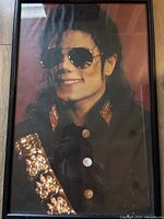 Front view of the framed Michael Jackson poster showcasing his image with black hair, aviator sunglasses, and black outfit with gold details.