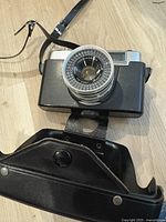 Photo of Yashica Minister III camera with 45mm Yashinon lens and attached black leather case showing lens front.