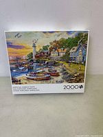 Front view of puzzle box showing full image of American harbor town with lighthouse, houses, boats, at sunset