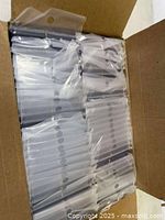 Opened box showing multiple stacks of transparent plastic card holders individually packaged.