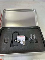 Close-up of Bernina Stitch Regulator foot and accessories in foam-lined metal tin