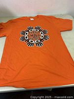 Full view of one orange "Every Child Matters" T-shirt laid out flat on a surface showing the front printed design.