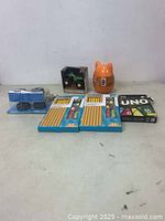Overview of all items in the lot including card game, pencils, grips, toy car, and container.