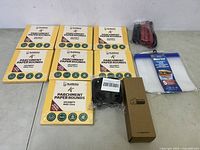 Eight boxes of Katbite parchment paper rounds (200 sheets each), black twist ties, small brown box, pack of five clip-on strainers laid out on floor.