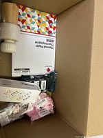 Box with ceramic grinder, thermal paper pack, packaged glasses cases, and other small items.