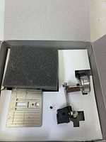 Top view of the accessory set metal parts in a white box insert with foam and cutouts for components