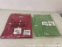 Two folded men's Kappa polo shirts in plastic bags, red and green colors, laid side by side on a white surface.