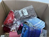 View of box showing a packaged block of chocolate or similar product, red water bottle, and blue and white patterned box among other items.