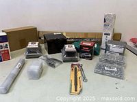 Photo showing assorted boxed and bagged hardware, tools, and accessories spread on a table against a light background.