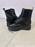 Pair of black lace-up boots shown from a three-quarter view, displaying the outer sides, platform sole, and laces