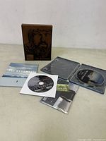 Full display of the opened media case with discs and inserts visible.