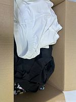 Box with white and black clothing items, some folded casually