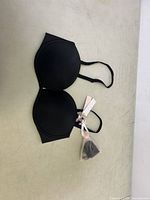 Black push-up bra laid flat on a light surface showing the entire bra structure including adjustable straps.