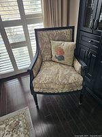 Front view of the Ethan Allen Empire style upholstered chair with floral upholstery and throw pillow