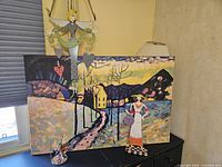 Four piece collection with framed Kandinsky-style colorful print in background, tin angel wall hanging, and two freestanding tin ladies in front.