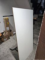 Folded white laminate tabletop leaning against the wall showing surface condition.