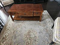 Front view of rectangular solid wood coffee table showing two drawers and lower shelf