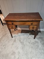 Front view of the antique console table showing three drawers and turned legs