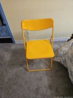 Front view of the bright yellow folding chair placed on carpet.