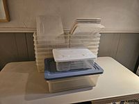18 clear plastic storage containers stacked with matching white lids visible, one lid gray.