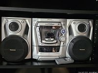 Full frontal shot showing the stereo main unit flanked by two speakers on either side with a remote placed in front.