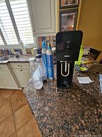 SodaStream carbonation machine with two carbonator canisters and two bottles placed on a kitchen counter.