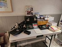 Full lot overview on table showing sewing machine, cases, tins, manuals and accessories