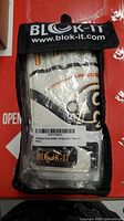 Front view of BLOK-IT goalkeeper gloves in original packaging showing branding and graphic design with white, black and orange colors.