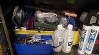 Mixed hand tools including wrenches, screwdrivers, pliers, and hardware parts stored in plastic bins with additional items like caulking tubes and alcohol bottles.