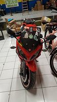 Front view of red sport-style electric motorcycle showing windshield with decorative stickers