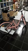Full right-side view of pink electric bicycle showing frame style, battery, rear hub motor, fenders.