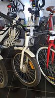 Front and side view of the white Daymak San Francisco electric bicycle showing front motor and handlebar details.