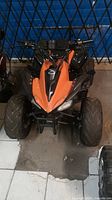 Front view of orange Daymak Sasquatch 1000 electric ATV showing front suspension, tires and handlebars