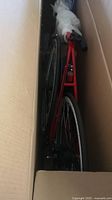 Top-down view of red bicycle frame and rear wheel inside shipping box