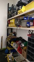 View of top and middle shelves showing plastic toolboxes, wire basket, yellow bins and parts organizer